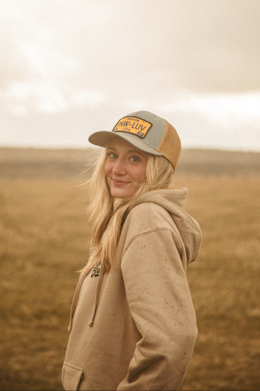 Person wearing a cap and hoodie in a field with a blurred background